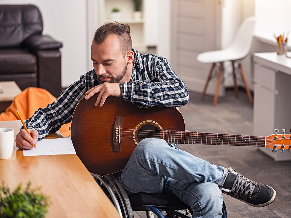 man writing a song with guitar